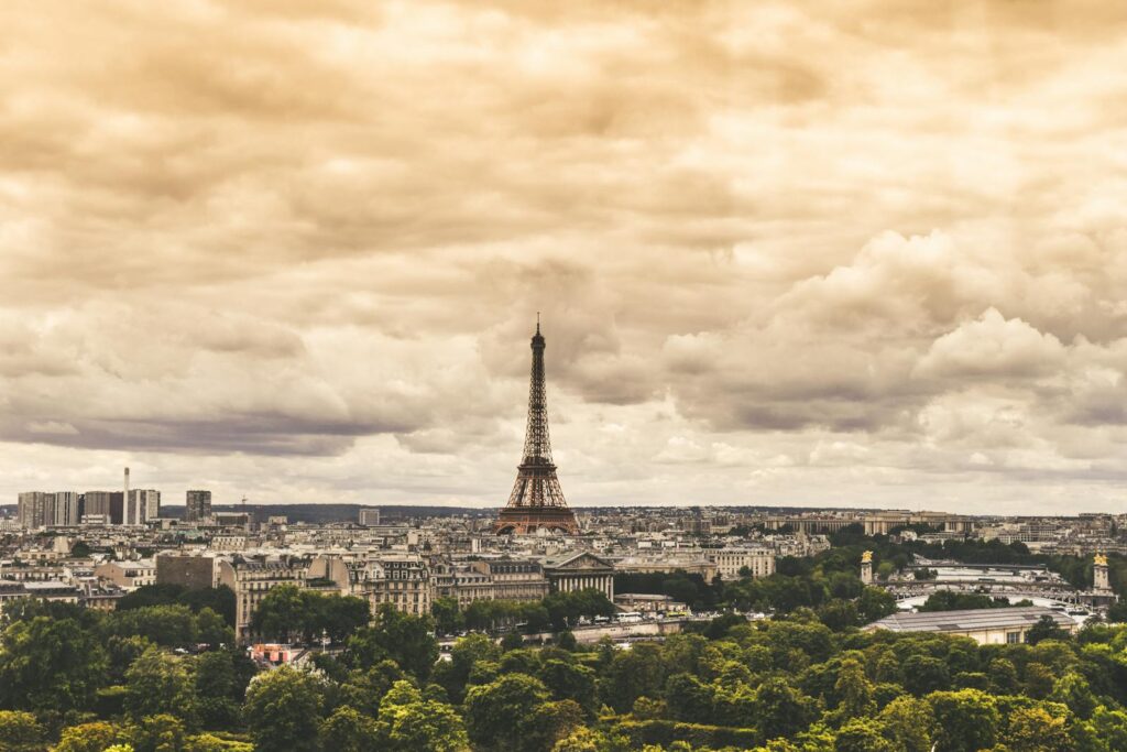 The Eiffel Tower standing tall over Paris, under a dramatic cloudy sky.
